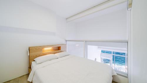 a bedroom with a white bed and a window at Yeongdeok Searest Poolvilla in Yŏngdŏk