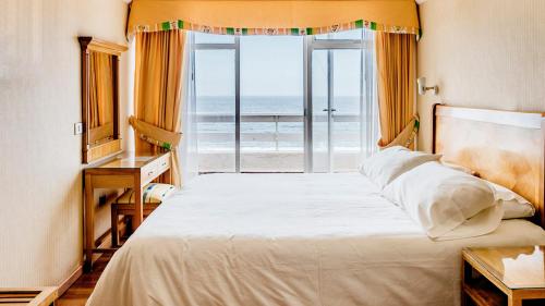 a bedroom with a bed with a view of the ocean at Hotel Nilahue in Viña del Mar