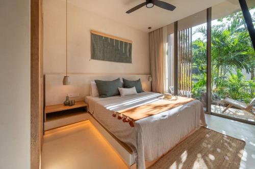 a bedroom with a bed and a large window at Amazing 1BR Tulum Jungle with Restaurant, Pool and Gym in Tulum