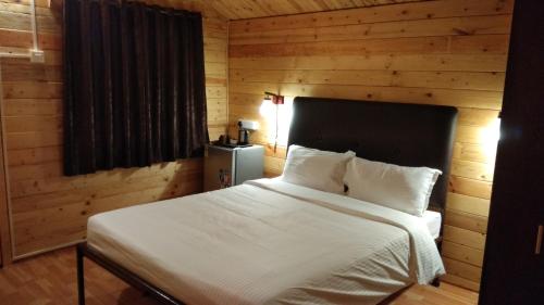 a bedroom with a white bed with a wooden wall at Lazy Frog Guest House in Cavelossim