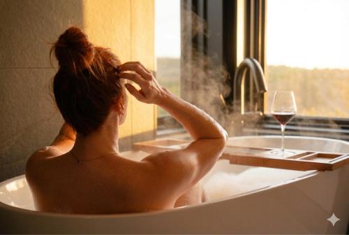 a woman sitting in a bath tub with a glass of wine at Ridge On The Chimney - 4 Cottages in Chimney Corner