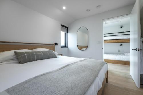 a white bedroom with a large bed and a mirror at Ridge On The Chimney - 4 Cottages in Chimney Corner