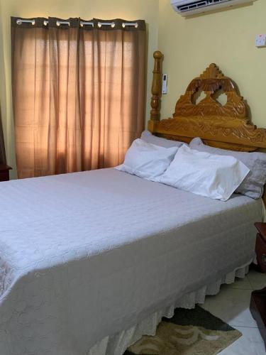 a bed with a wooden headboard in a bedroom at The Cozy Haven Bed and Breakfast in Montego Bay