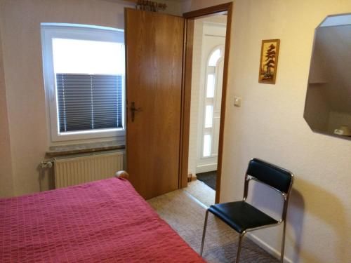 ein Schlafzimmer mit einem Bett, einem Stuhl und einem Fenster in der Unterkunft Ferienwohnung Büll in Burg auf Fehmarn