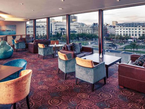 a restaurant with couches and tables and windows at Mercure Manchester Piccadilly Hotel in Manchester