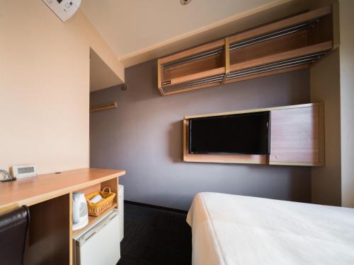 a hotel room with a bed and a flat screen tv at Super Hotel Inn Kurashiki Mizushima in Kurashiki