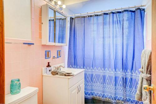 a bathroom with a blue shower curtain and a sink at 90s Condo| King Bed | 65” Smart TV | Arcade Game in Elmwood Park
