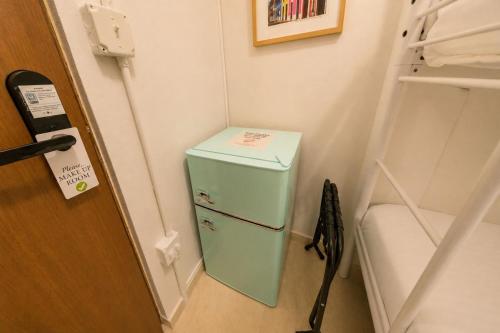 a small green refrigerator in a corner of a room at Room 4: Minimalist Bunk Room w/ Free Parking | San Juan in San Juan