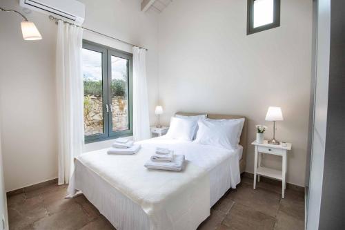 a white bedroom with a bed with towels on it at Villa Ares in Bogdanátika