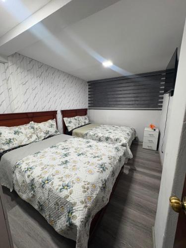 ein Schlafzimmer mit zwei Betten und einer Wand in der Unterkunft Departamentos en Cuenca in Cuenca