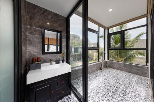 a bathroom with a sink and a large window at Cát Bà Sena Valley Retreat in Xuan Dam