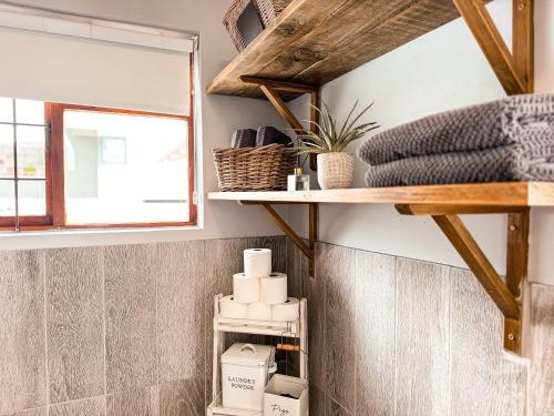 a bathroom with a shelf with towels and a window at Normandie On Sea in Hermanus