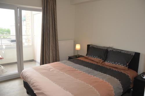 a bedroom with a large bed and a balcony at 4B @ Longchamp in Ostend