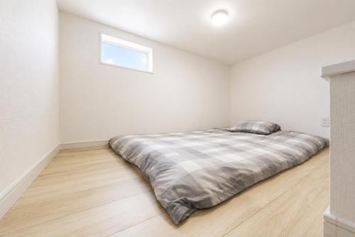 a white bedroom with a bed in the corner at BALOH Wadamisaki in Kobe