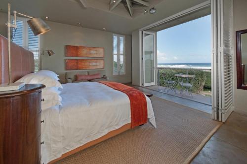 a bedroom with a bed and a view of the ocean at Mosselberg on Grotto Beach in Hermanus