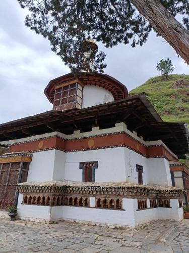 a building with a hill in the background at Drukyul Kora Tours & Treks in Thimphu