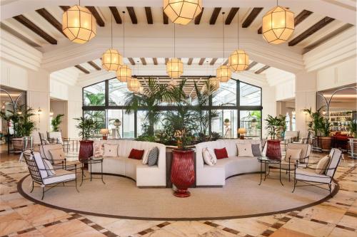 a lobby with white furniture and large windows at Meliá Isla Canela in Isla Canela