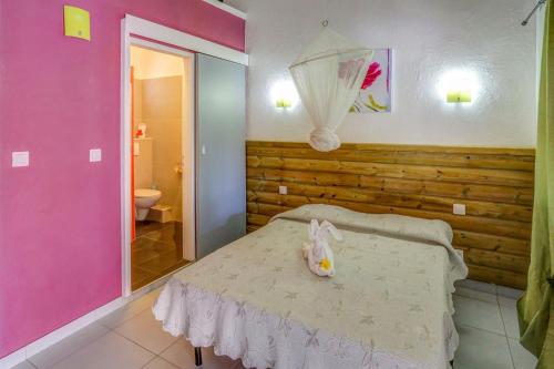 a bedroom with a bed and a pink wall at Antilles Liberte in Sainte-Anne
