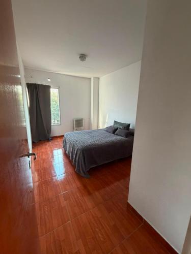 a bedroom with a bed and a wooden floor at Departamento en Ezeiza - SA in La Unión