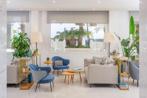 a living room with blue chairs and tables at Hotel Las Arenas, Affiliated by Meliá in Benalmádena