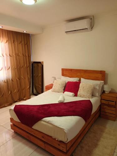 a bedroom with a large wooden bed with red pillows at Pleasant Field Bed And Breakfast in Gaborone