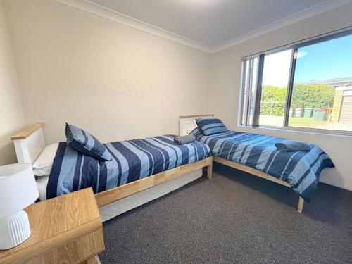 two beds in a room with a window at Pacific Court 2 in South West Rocks