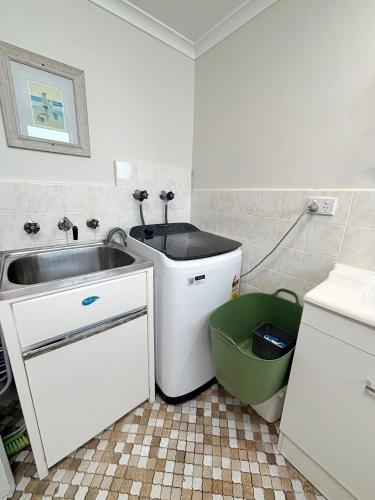 a small kitchen with a sink and a trash can at Pacific Court 2 in South West Rocks