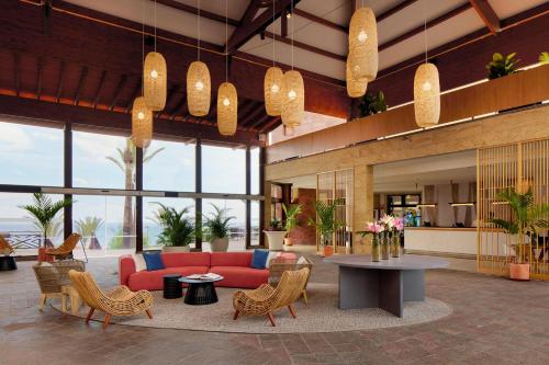 a lobby with a red couch and a table and chairs at Meliá Jardines del Teide - Adults Only in Adeje