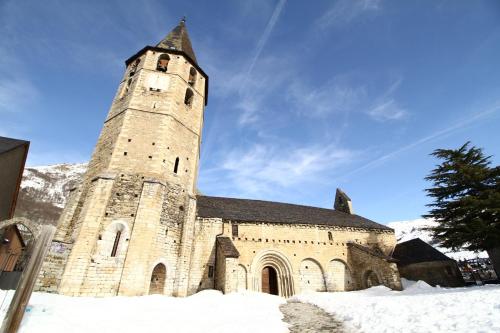 a church with a tall tower in the snow at Hotel SNÖ Mont Romies in Salardú