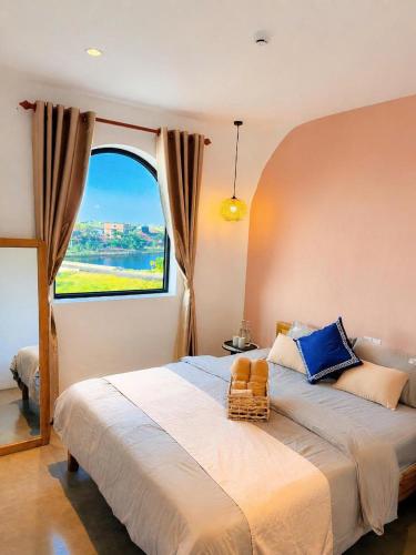 a bedroom with a large bed with a large window at La Riva Riverside Hue Hotel & Rooftop in Hue