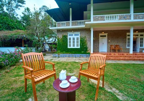 two chairs and a table in front of a house at Ministers Mansion Kanthalloor Pool Resort by VOYE HOMES in Kanthalloor
