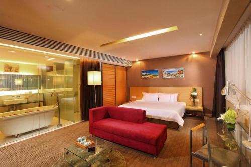 a hotel room with a bed and a tub and a red chair at Catic Hotel--Adjacent Buliding in Zhuhai