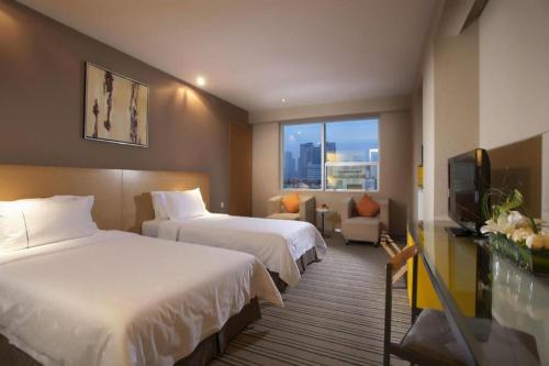 a hotel room with two beds and a television at Catic Hotel--Adjacent Buliding in Zhuhai