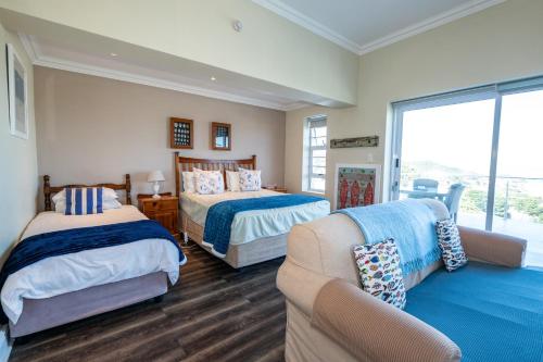 a bedroom with two beds and a couch at The Lookout Guest House in Port Alfred