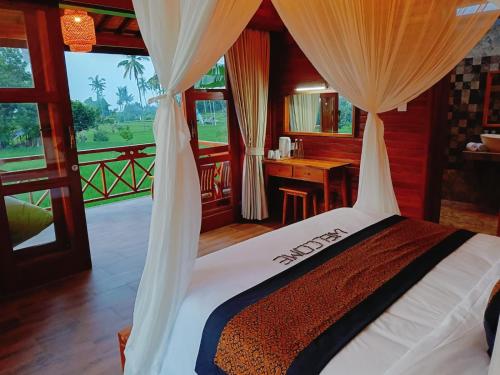 a bedroom with a bed with a window and a desk at Dapha Eco Lodge Lovina in Lovina