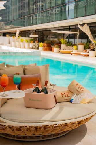 a wicker basket with bottles of wine sitting next to a swimming pool at ME by Meliá Dubai in Dubai