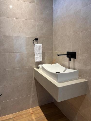 a bathroom with a white sink and a tile wall at Ocean Inn- Sector el Bluff in Bottom House