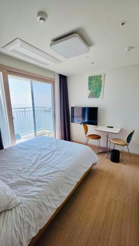 a bedroom with a bed and a desk and a window at 양양 죽도해변호텔 오션뷰스테이 일출뷰 바다뷰 힐링뷰 낭만뷰 넷플릭스완 in Saetchak