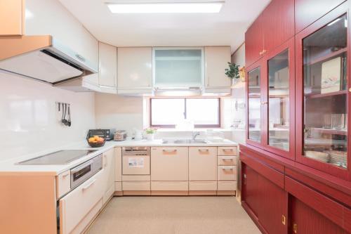 a kitchen with white counters and red cabinets at Cove琴平 - 1組貸切 最大8名 こんぴらさん徒歩すぐ in Kotohira