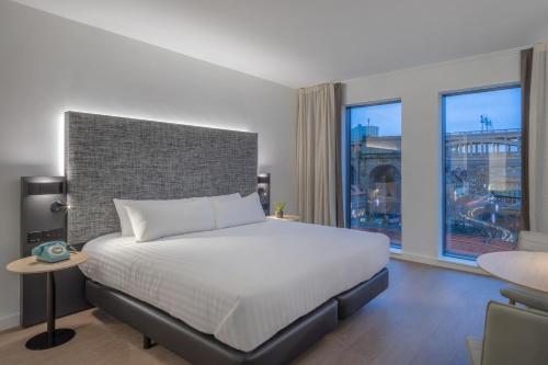a bedroom with a white bed and a large window at INNSiDE by Meliá Newcastle in Newcastle upon Tyne