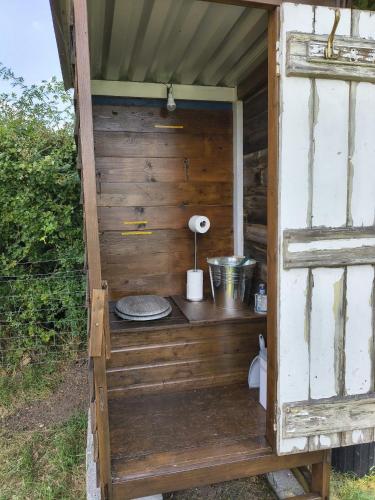 a wooden outhouse with a table and a lamp in it at Hilltop Farm Camping in Haselbury Bryan