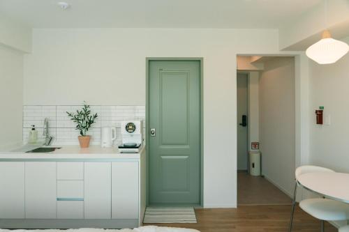 a kitchen with white cabinets and a green door at 버터인 강릉역 중앙시장 월화거리 교리단길 도보 10분 in Gangneung