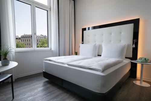 a bedroom with a large white bed and a window at INNSiDE by Meliá Leipzig in Leipzig