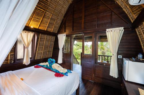 a bedroom with a bed with a stuffed animal on it at Dream Beach Kubu & SPA by ABM in Nusa Lembongan