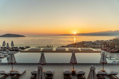 a view of the pool at a resort with the sunset at INNSiDE by Meliá Crete Elounda in Elounda