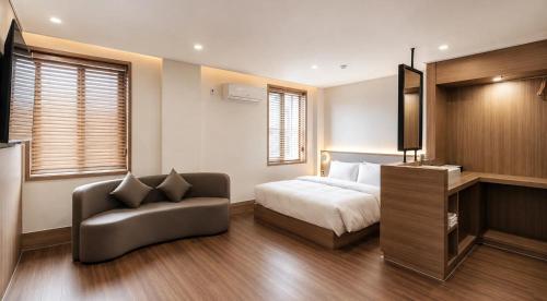 a bedroom with a bed and a chair and a television at 에이치에비뉴 상주터미널점 in Sangju