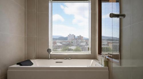 a white bath tub in a bathroom with a window at 에이치에비뉴 상주터미널점 in Sangju