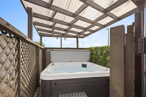 a hot tub on a deck with a pergola at Brookside Residence in Rolleston