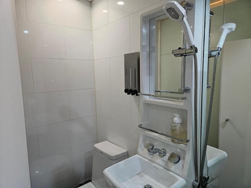a white bathroom with a shower and a sink at SimpleStay Hotel in Jongno in Seoul