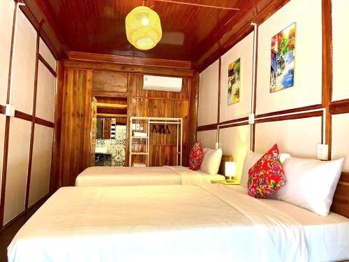 two beds in a bedroom with wooden walls at Woodstock Beach Camp in Cat Ba